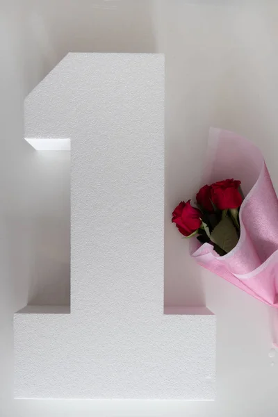 Strauß roter Rosen in rosa Papier und eine Zahl, Jahrestag — Stockfoto