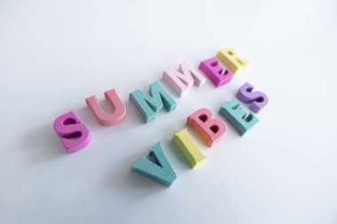 Beyaz arka planda izole edilmiş renkli ahşap harflerden oluşan bir yaz kelimesi.