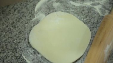 Mutfağa un serpiştiren ve hamuru saran bir kadın