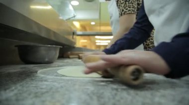 Mutfakta kurabiye yapmak için hamuru yuvarlayan iki kadın