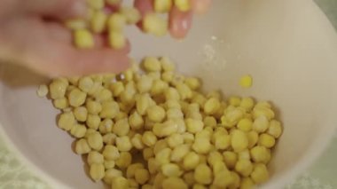 Bir kadın nohutlara dokunuyor ve onları kaseye karıştırıyor.