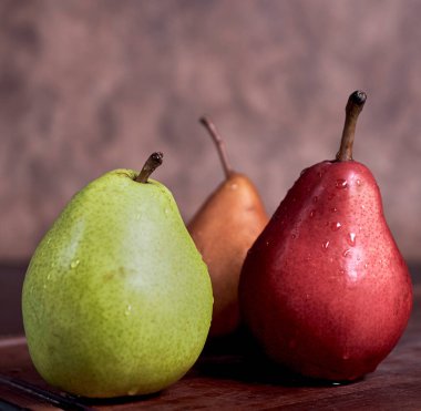 Farklı renkte armutlar. Sarı, yeşil ve kırmızı. Sırtı ahşap.