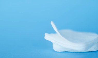 Mavi arka planda organik pamuk pedleri, kozmetik ürünleri ve makyaj malzemesi