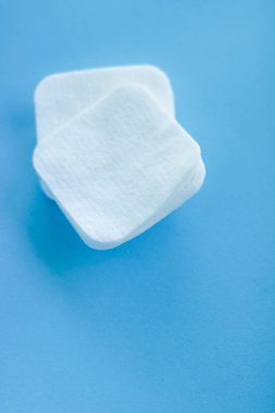 Mavi arka planda organik pamuk pedleri, kozmetik ürünleri ve makyaj malzemesi