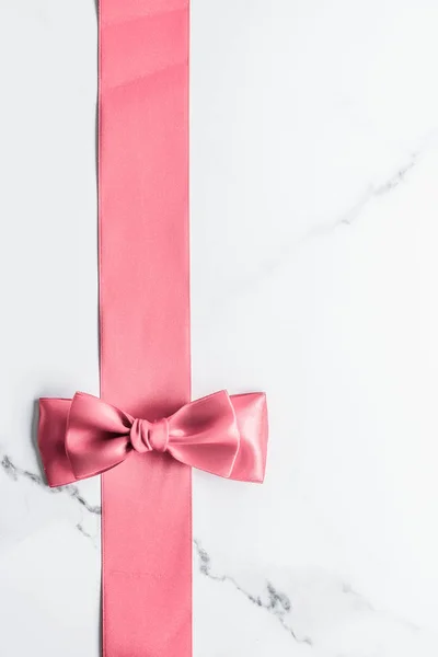 Coral silk ribbon and bow on marble background, girl baby shower — Stock Photo, Image