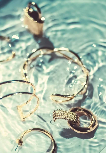Arany karkötők, fülbevalók, gyűrűk, ékszerek a smaragd vizes bac — Stock Fotó