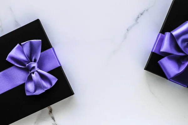 Luxusní prázdninové dárky s levandulovou hedvábnou stuhou a lukem na mramoru — Stock fotografie