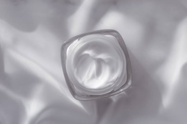 İpek arka planda yüz kremi nemlendirici kavanozu, nemlendirici cilt