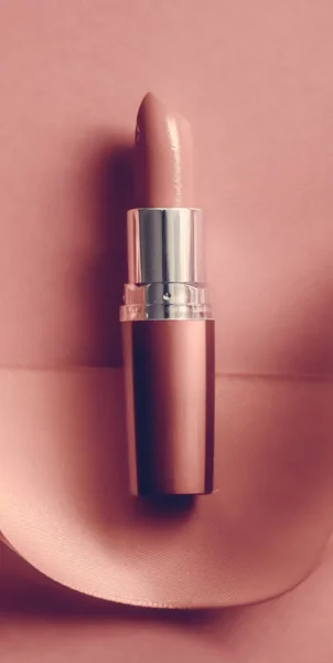Luxury lipstick and silk ribbon on blush pink holiday background