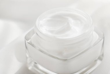 Face cream moisturizer jar on silk background, moisturizing skin clipart