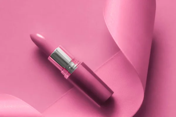 Luxury lipstick and silk ribbon on pink holiday background, make