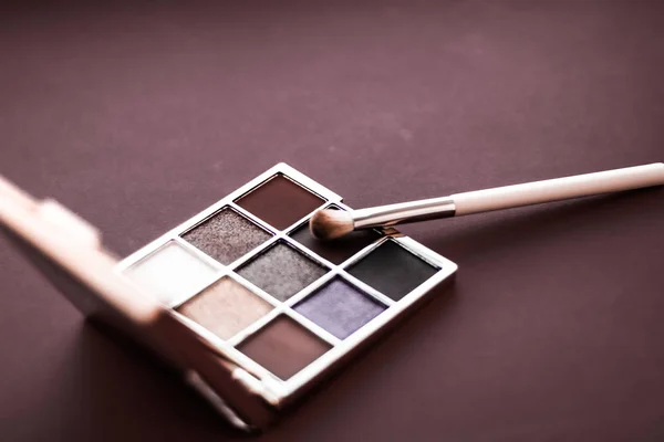 Eyeshadow palette and make-up brush on chocolate background, eye