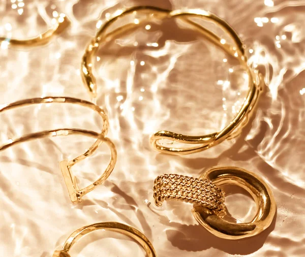 Arany karkötők, fülbevalók, gyűrűk, ékszerek arany víz backgr — Stock Fotó