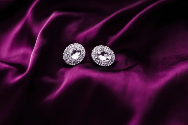 Роскошные бриллиантовые серьги на темно-розовой шелковой ткани, праздничная гламу — стоковое фото