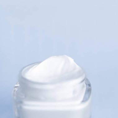 Mavi arka planda yüz kremi nemlendirici kavanozu, nemlendirici cilt