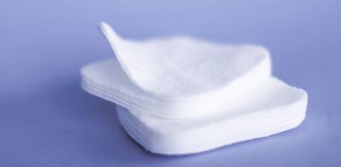 Mor arka planda organik pamuk pedleri, kozmetik ürünleri ve makyaj 