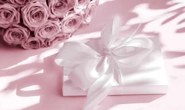 Luxury holiday silk gift box and bouquet of roses on blush pink