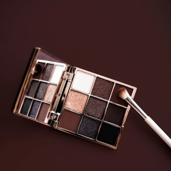 Eyeshadow palette and make-up brush on chocolate background, eye