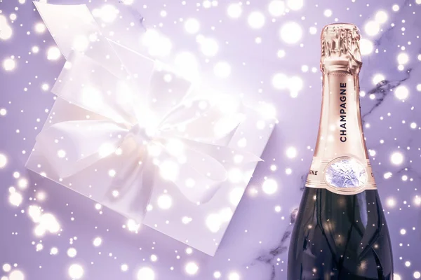 Bouteille de champagne et boîte cadeau sur des paillettes de vacances violettes, New Yea — Photo