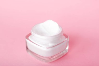 Pembe arka planda yüz kremi nemlendirici kavanozu, nemlendirici cilt