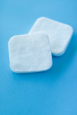 Mavi arka planda organik pamuk pedleri, kozmetik ürünleri ve makyaj malzemesi