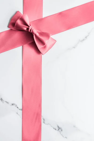 Coral silk ribbon and bow on marble background, girl baby shower — Stock Photo, Image