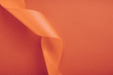 Turuncu arka planda soyut kıvrımlı ipek kurdele, özel lüks.