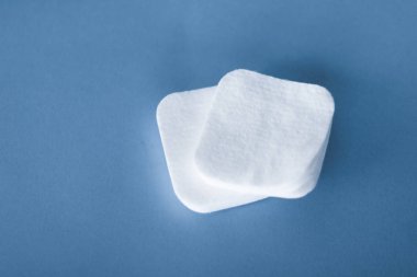 Mavi arka planda organik pamuk pedleri, kozmetik ürünleri ve makyaj malzemesi