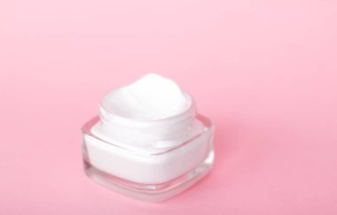 Pembe arka planda yüz kremi nemlendirici kavanozu, nemlendirici cilt