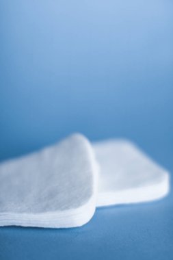 Mavi arka planda organik pamuk pedleri, kozmetik ürünleri ve makyaj malzemesi
