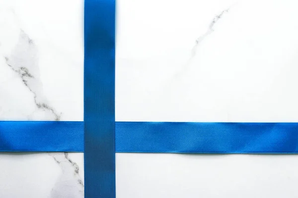 Modrá hedvábná stuha a luk na luxusním mramorovém pozadí, prázdninový FL — Stock fotografie