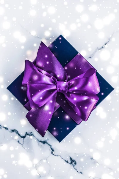 Winter holiday gift box with purple silk bow, snow glitter on ma — Stock Photo, Image