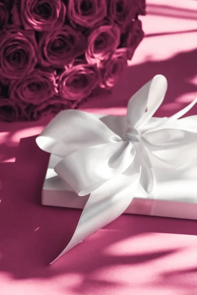 Luxury holiday silk gift box and bouquet of roses on pink backgr