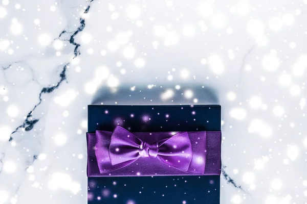 Zima wakacje pudełko z fioletowym jedwabnym łukiem, śnieg brokat na ma — Zdjęcie stockowe