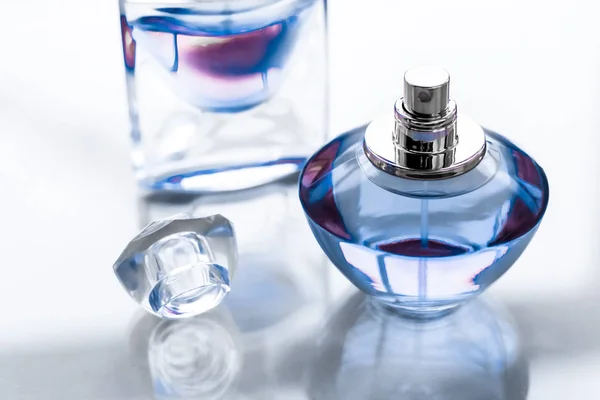 Niebieska butelka perfum na błyszczącym tle, słodki kwiatowy zapach, gl — Zdjęcie stockowe