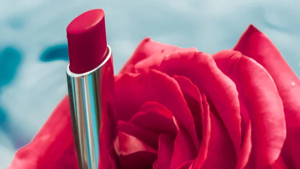 Lápiz labial rojo y flor de rosa sobre fondo líquido, gl impermeable —  Fotos de Stock