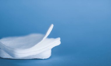 Mavi arka planda organik pamuk pedleri, kozmetik ürünleri ve makyaj malzemesi