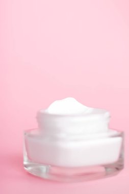Pembe arka planda yüz kremi nemlendirici kavanozu, nemlendirici cilt