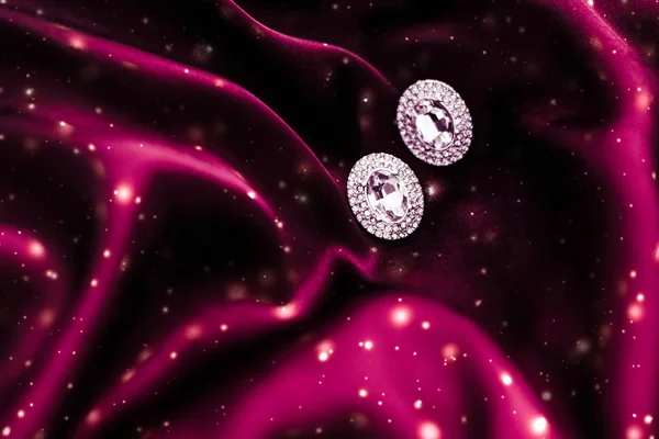 Luxury diamond earrings on dark red silk with snow glitter, holi — Stock Photo, Image