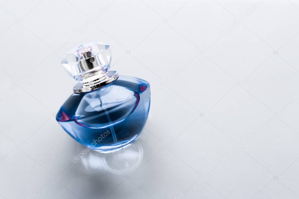 Blue perfume bottle on glossy background, sweet floral scent, gl