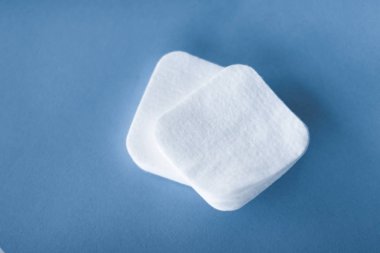 Mavi arka planda organik pamuk pedleri, kozmetik ürünleri ve makyaj malzemesi