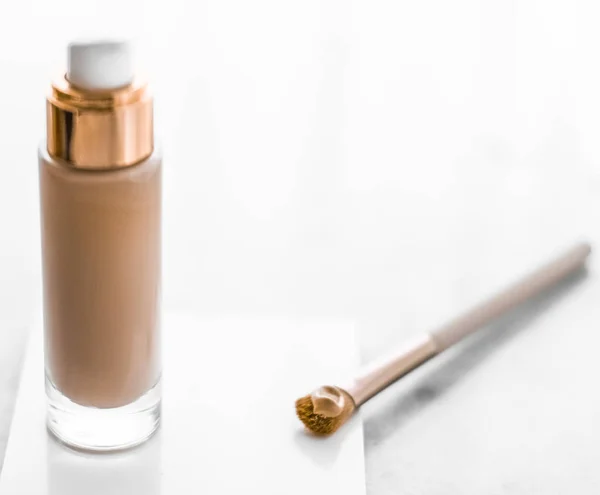 Makeup foundation bottle and contouring brush on marble, make-up