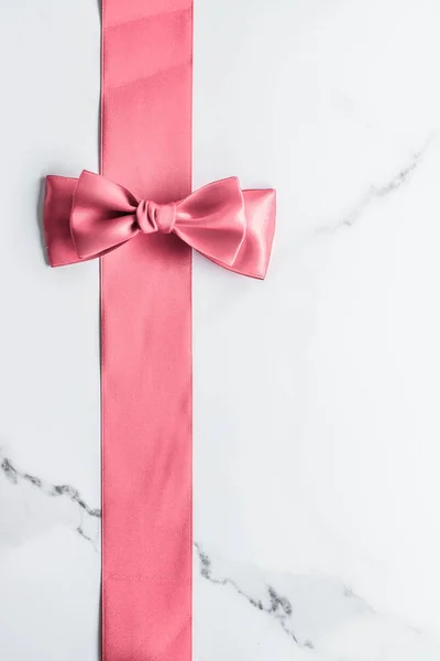 Coral silk ribbon and bow on marble background, girl baby shower