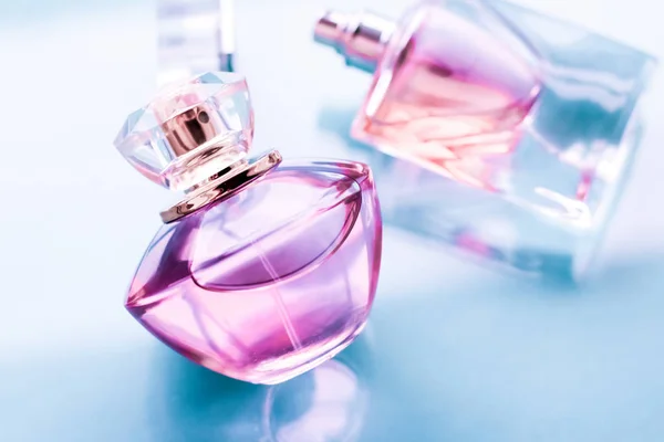 Pink perfume bottle on glossy background, sweet floral scent, gl