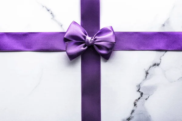 Purple silk ribbon and bow on luxury marble background, holiday