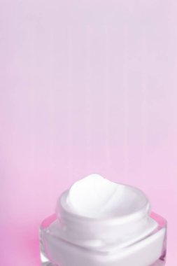 Pembe arka planda yüz kremi nemlendirici kavanozu, nemlendirici cilt