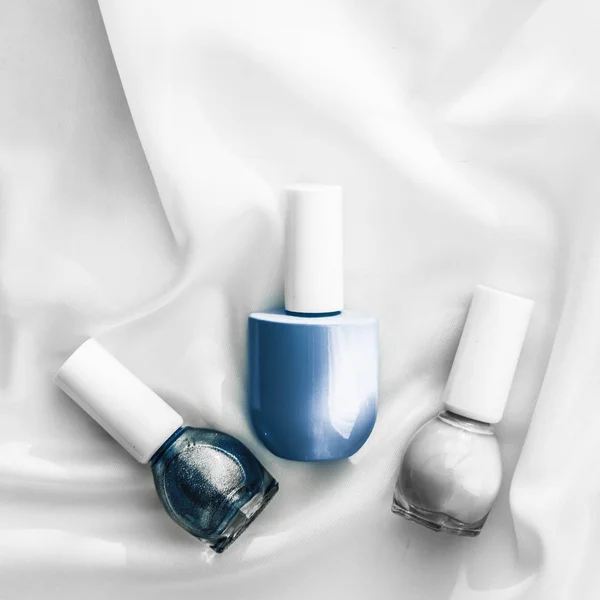 Nail polish bottles on silk background, french manicure products