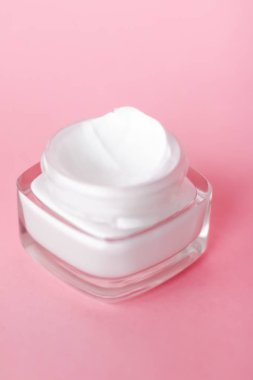 Pembe arka planda yüz kremi nemlendirici kavanozu, nemlendirici cilt