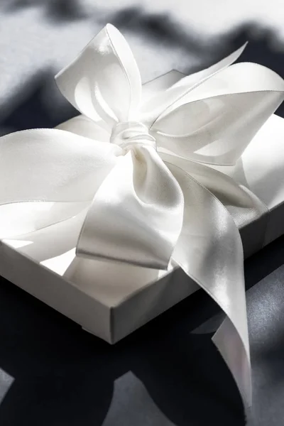 Розкішна святкова біла подарункова коробка з шовковою стрічкою та бантом на чорному — стокове фото
