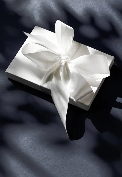 Luxury holiday white gift box with silk ribbon and bow on black